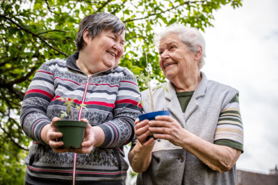 Young and elderly patient smiling at each other while holding flower pot